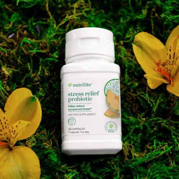 Nutrilite Stress Relief Probiotic bottle on a bed of greens and flowers